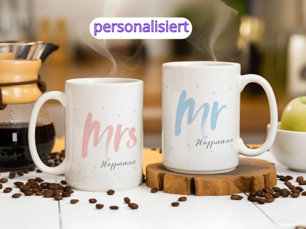 Personalisierte Tassen-Set mit den Aufschriften 'Mr Hoffmann' und 'Mrs Hoffmann' in Blau und Rosa, ideal als Geschenk für Paare. Perfekt für den gemeinsamen Kaffeegenuss am Morgen.